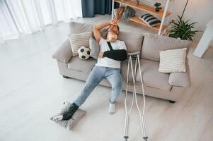 Laying ,down and suffering from the pain. Man with crutches is at home indoors. Having injuries photo