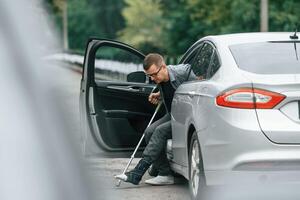 Injured man with crutches,, is going out from the car photo