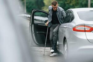Injured ,man with crutches is going out from the car photo