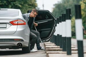 Injured ,man with crutches is going out from the car., photo