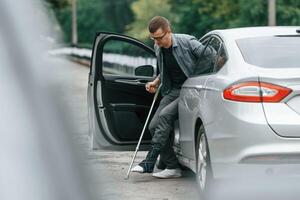 Injured man with crutches is going out from ,the car. photo
