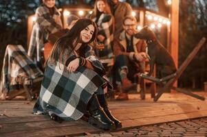 Portrait ,is sitting in front of her friends. Group of people is spending time together on the backyard at evening time photo