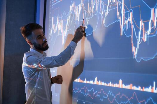 Man, is standing near projector and showing graphs and business graphs photo