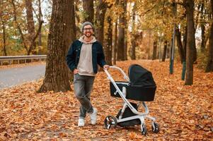 Enjoying ,the nature. Man with pram is having a walk in the autumn park photo