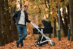 Man with pram, is having a walk in the autumn park photo