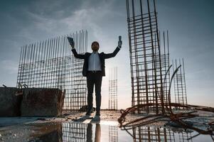 With hands up. Standing at evening time. Businessman in formal clothes is on the construction site photo