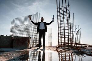 With, hands up. Standing at evening time. Businessman in formal clothes is on the construction site photo