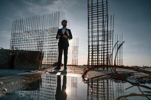 Beautiful, background with evening sunlight. Businessman in formal clothes is on the construction site photo