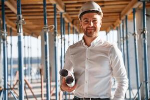Standing and, smiling. Man is working on the construction site at daytime photo