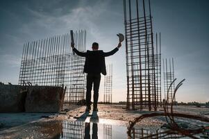 With ,hands up.. Standing at evening time. Businessman in formal clothes is on the construction site photo