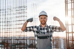 Showing biceps. Conception of succes. Man is working on the construction site at daytime photo