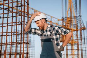 Feeling, bad. Having headache. Man is working on the construction site at daytime photo
