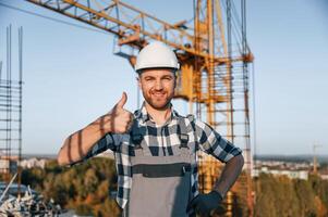 Standing and smiling. Man is working on the construction site at daytime photo