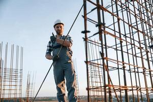 Holding ,metal ,object in hands. Man is working on the construction site at daytime photo