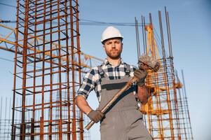 With big hammer ,in, hands. Man is working on the construction site at daytime photo