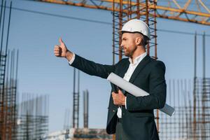 Showing thumb up. Businessman in formal clothes is on the construction site at daytime photo