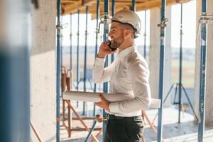 Using phone. Manager is in the formal clothes.. Man, is working on the construction site at daytime photo