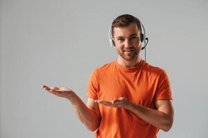 Conception of call center. ,In headset. Handsome man is in the studio against white background photo