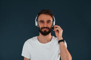 In headphones. Handsome man is ,in the studio against blue background photo