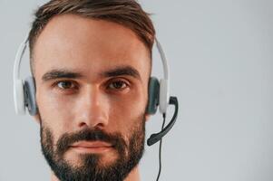Close up portrait. In headset with microphone. .Handsome man is in the studio against white background photo