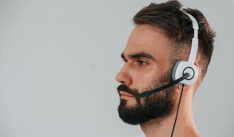 Side view. In headset. Handsome man is in the, studio against white background photo