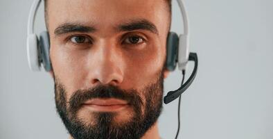 Close up portrait.. In headset with microphone. Handsome man is in the studio against white background photo
