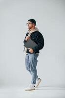 Walking ,and ,holding laptop. Handsome man is in the studio against white background photo