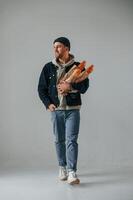 Man in hat is holding, baguettes. Guy is in the studio against white background photo