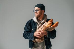 With ,,bunch of baguettes in hands., Handsome man is in the studio against white background photo
