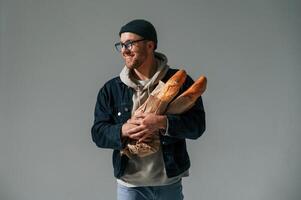 With bunch of baguettes in hands.. Handsome man is in the studio against white background photo