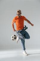 Doing tricks, playing with soccer ball.. Handsome man is in the studio against white background photo
