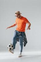 Doing tricks, playing, with soccer ball. Handsome man is in the studio against white background photo