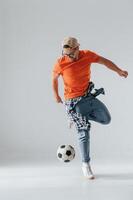 Doing tricks, playing with ,soccer ball. Handsome man is in the studio against white background photo