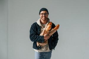 With bunch of, baguettes in hands. Handsome man is in the studio against white background photo