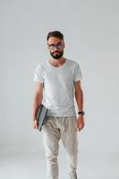 Front view. Holding laptop.. Handsome man is in the studio against white background photo