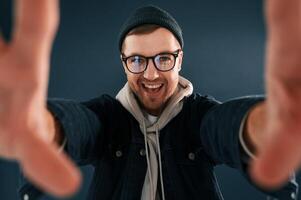 Making ,the photo by hands, pretending. Smiling. Handsome man is in the studio against blue background