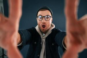 Making the ,photo by hands, pretending. Smiling. Handsome man is in the studio against blue background photo