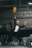 Hanging on the crane hook. Manager in ,black, formal wear at the factory photo