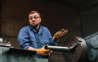 Man have no idea what to do with automatic machine. Factory worker in blue uniform is indoors photo
