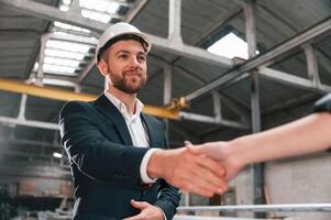 Handshake with partner.. Manager in black formal wear at the factory photo