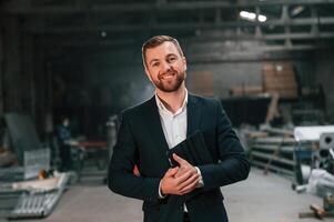 Friendly manager in black formal wear, at the factory photo