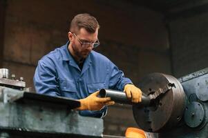 Operating ,the automatic machine. Factory worker in blue uniform is indoors photo