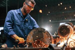 Many, of the sparks. Welding the metal. Factory worker in blue uniform is indoors photo