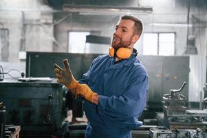 Working by using digital tablet. Man at the factory that is in blue uniform is indoors photo