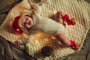 Little ,baby is lying down, on the ground. In Christmas clothes. Conception of new year photo