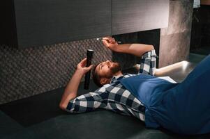 Fixing,, the siphone. Lying down on the floor. Plumber in blue uniform is at work in the bathroom photo