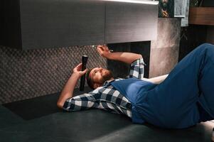 Using flashlight. Fixing water tap. Plumber in blue uniform is at work in the bathroom photo