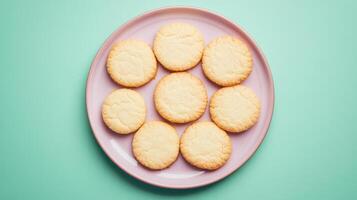 Overhead Shot of Nine Round, Pale Cookies on a Pastel Pink Plate Against a Mint Green Background photo