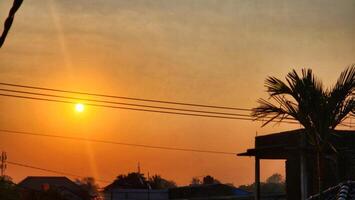 the sun is setting over a village with palm trees photo