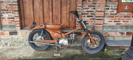 a brown motorcycle parked next to a brick wall photo